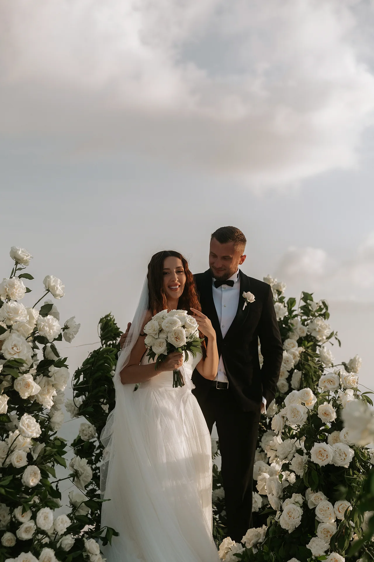 A couple at the floral arch above the ocean